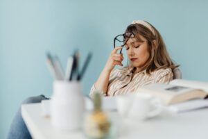 Person looking stressed and tired, rubbing temples, with subtle blue filter, exhaustion - tired emotions