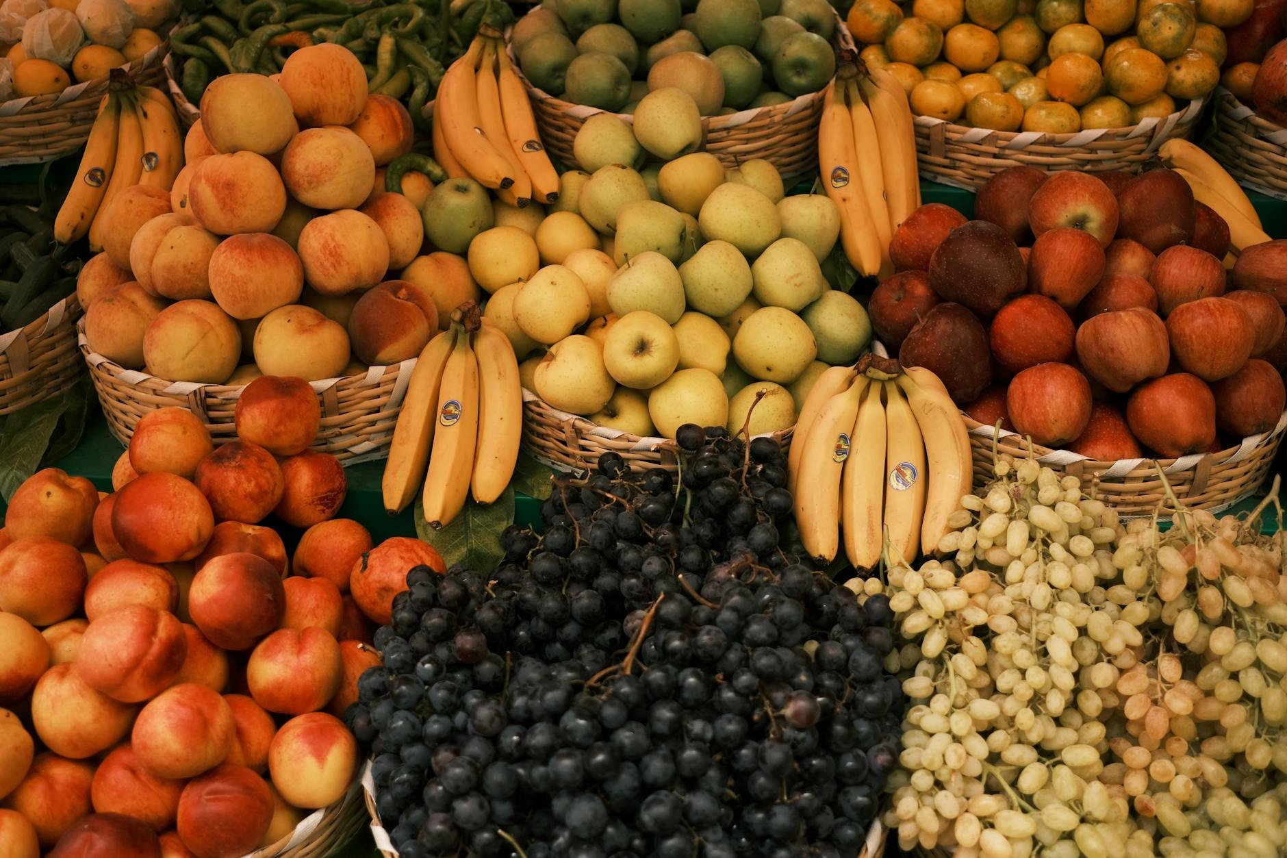 Assortment of whole, unprocessed fruits (apples, pears, oranges, bananas) in a woven market basket - fruit sugar metabolism