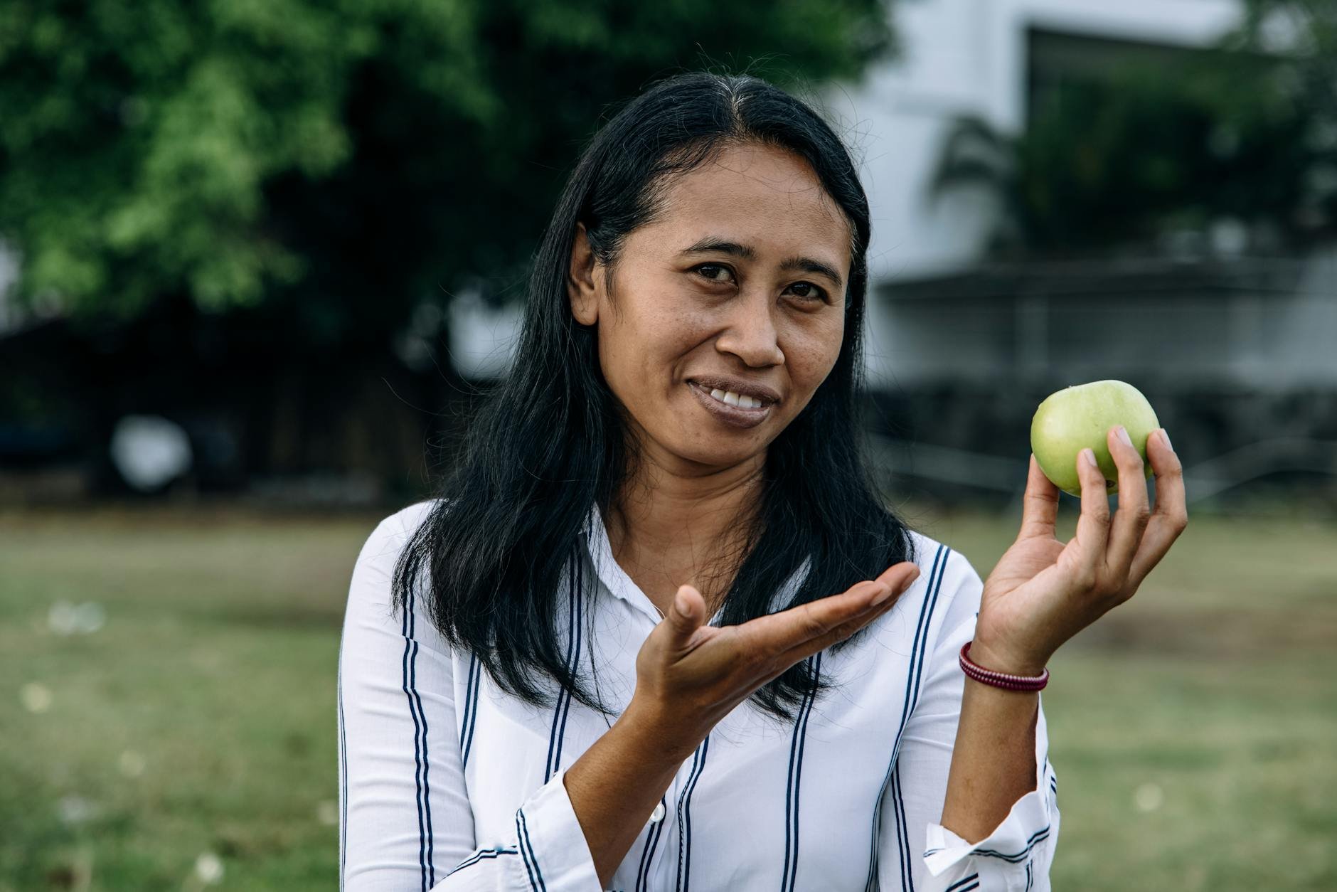 Happy person enjoying a fresh apple outdoors in a park, smiling - fruit sugar metabolism