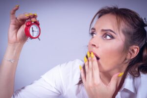 woman looking at alarm clock 3 AM frustrated - waking up at 3am