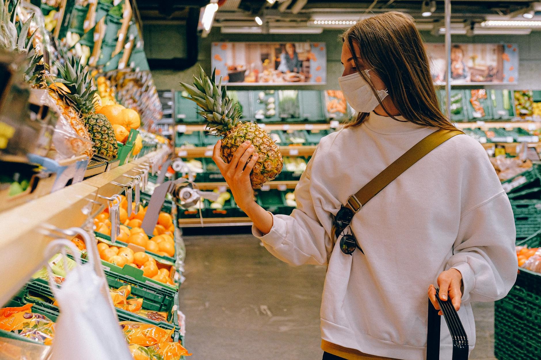 Woman thoughtfully choosing a variety of seasonal fruits in a bright, modern European grocery store - fruit sugar metabolism