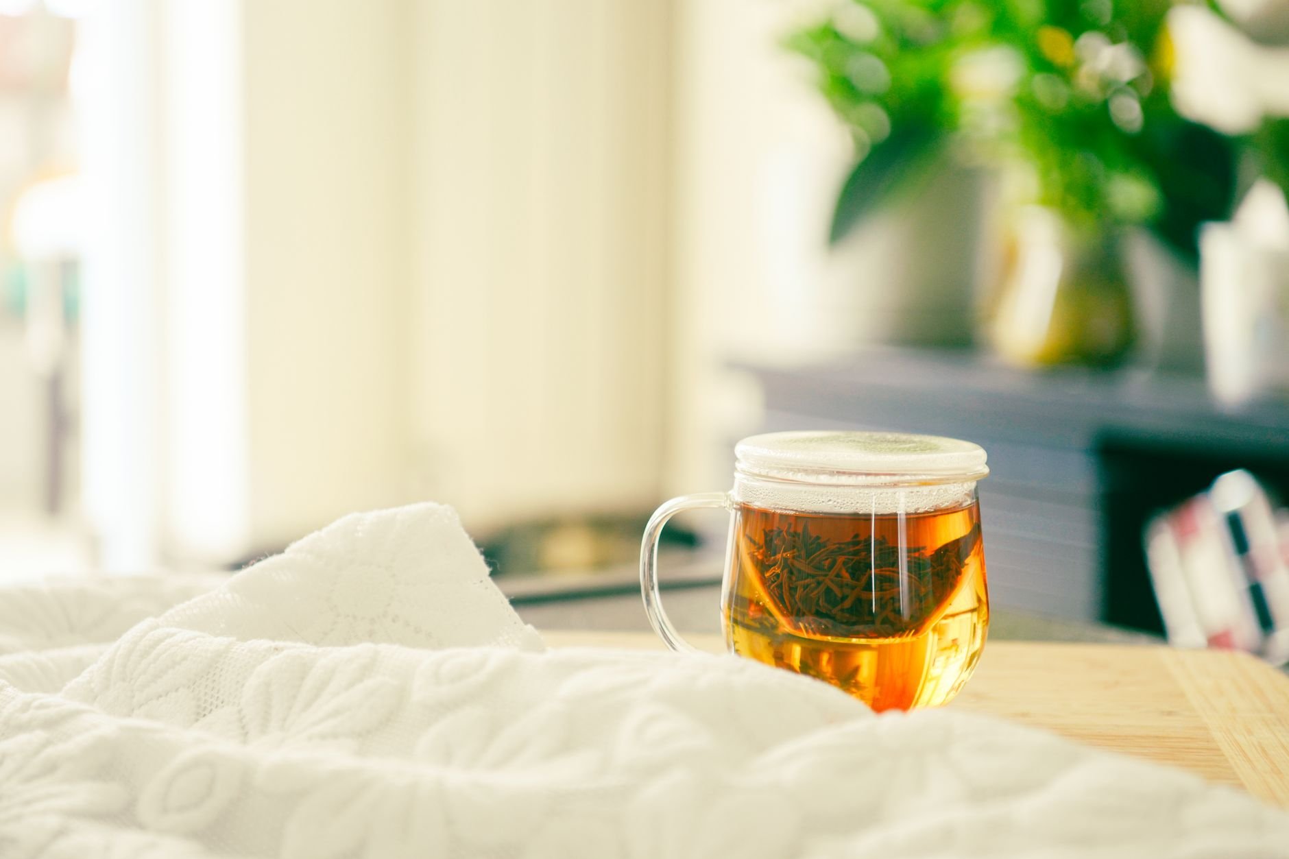Herbal tea cup with a calming book and soft blanket on a bedside table - Magnesium for sleep